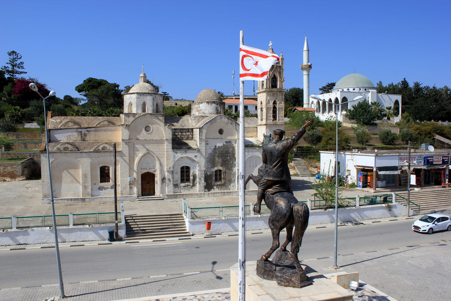Centro di Rizokarpaso/Dipkarpaz nella penisola di Karpas, Cipro, con la chiesa di Agios Synesios, la moschea e il monumento ad Atatürk. Foto: Julian Nyča - CC BY-SA 3.0